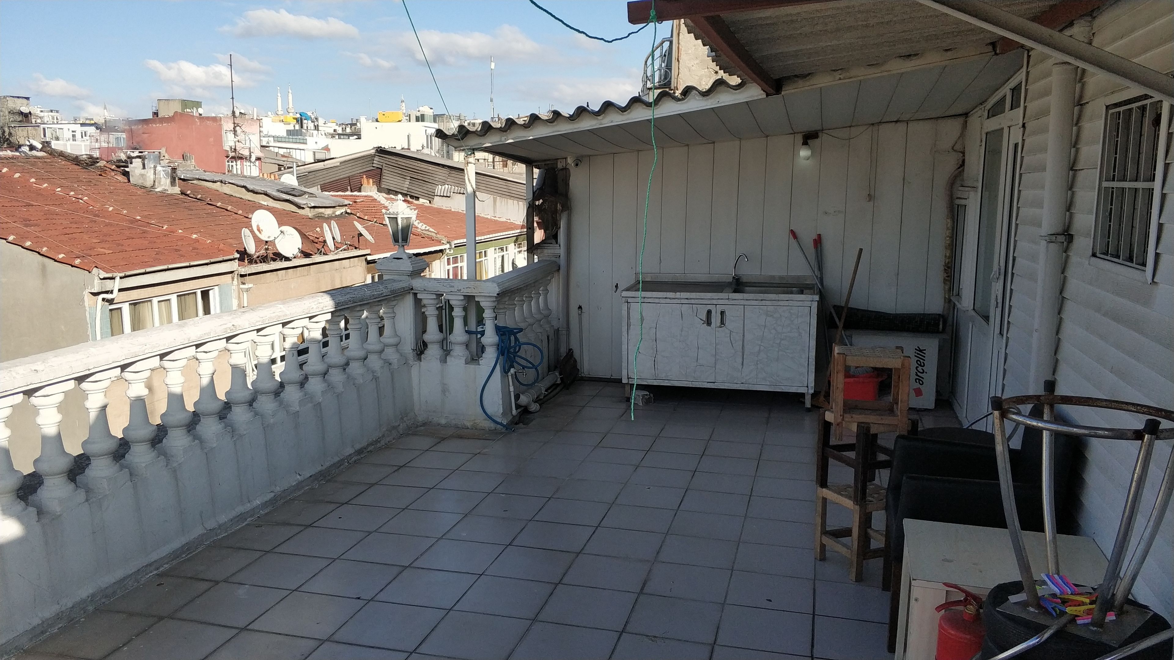 Ein Balkon mit Fliesenboden, einem weißen Schrank und einem Fahrrad.