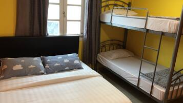 A bunk bed room with a single bed and a window.