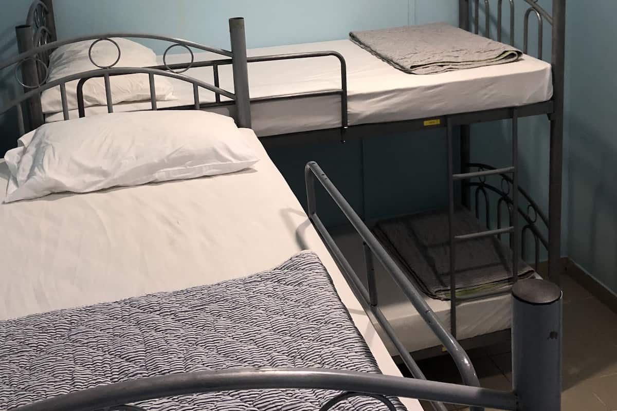 A bunk bed with a metal frame, white bedding, and a blue wall.
