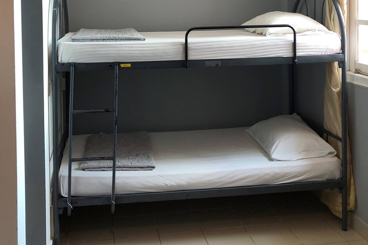 A bunk bed room with a ceiling vent and a window with curtains.