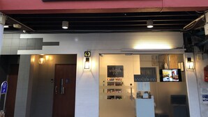 Exterior de un hotel llamado 'Snooze Inn', con un letrero sobre la entrada, el número '43' en la pared y una puerta cerrada.