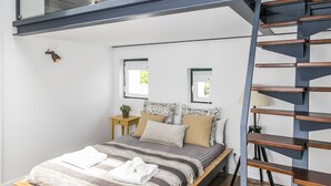 A modern bedroom with a skylight, a bed with a wooden frame, a built-in desk, and a spiral staircase. - LxWay Lisboa aos Poiais (Lisbon)