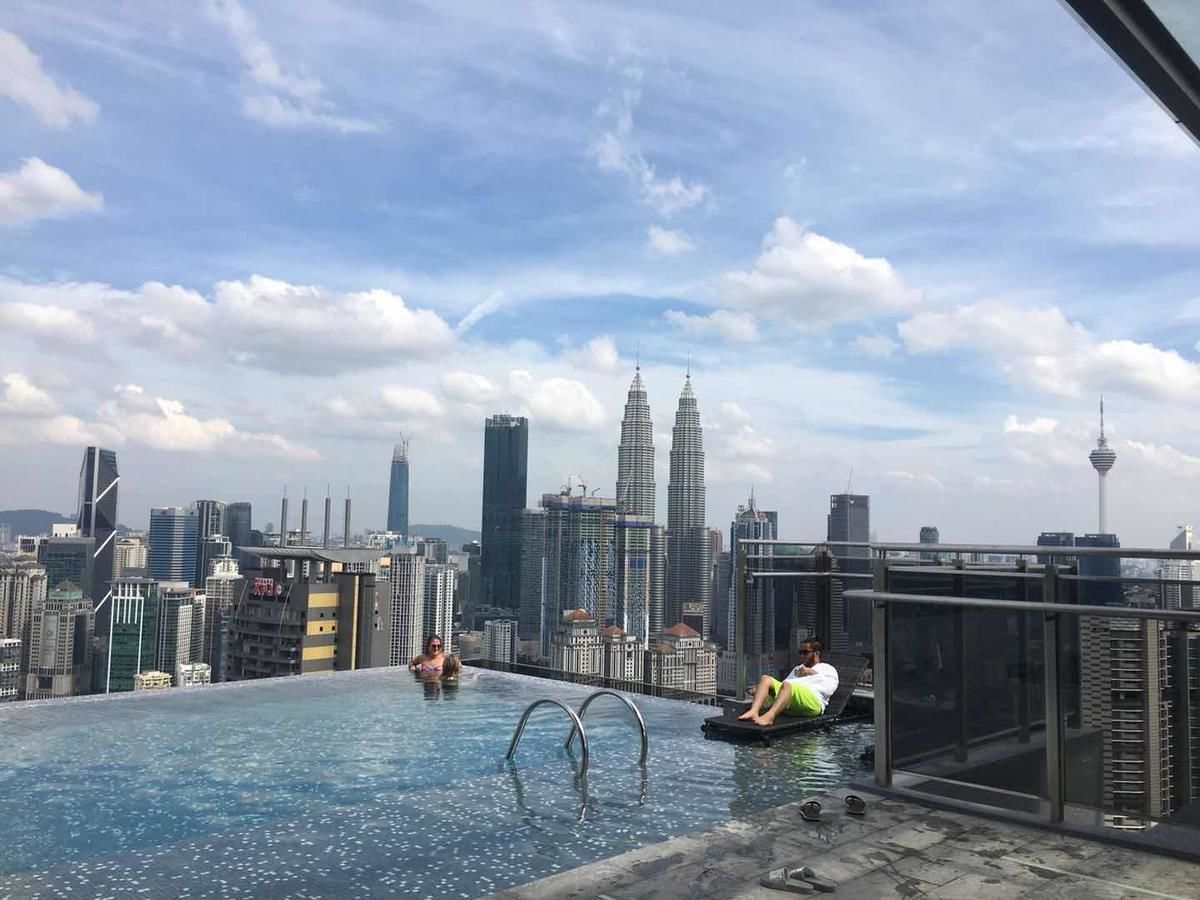 An infinity pool with a city skyline in the background, including the Petronas Towers.