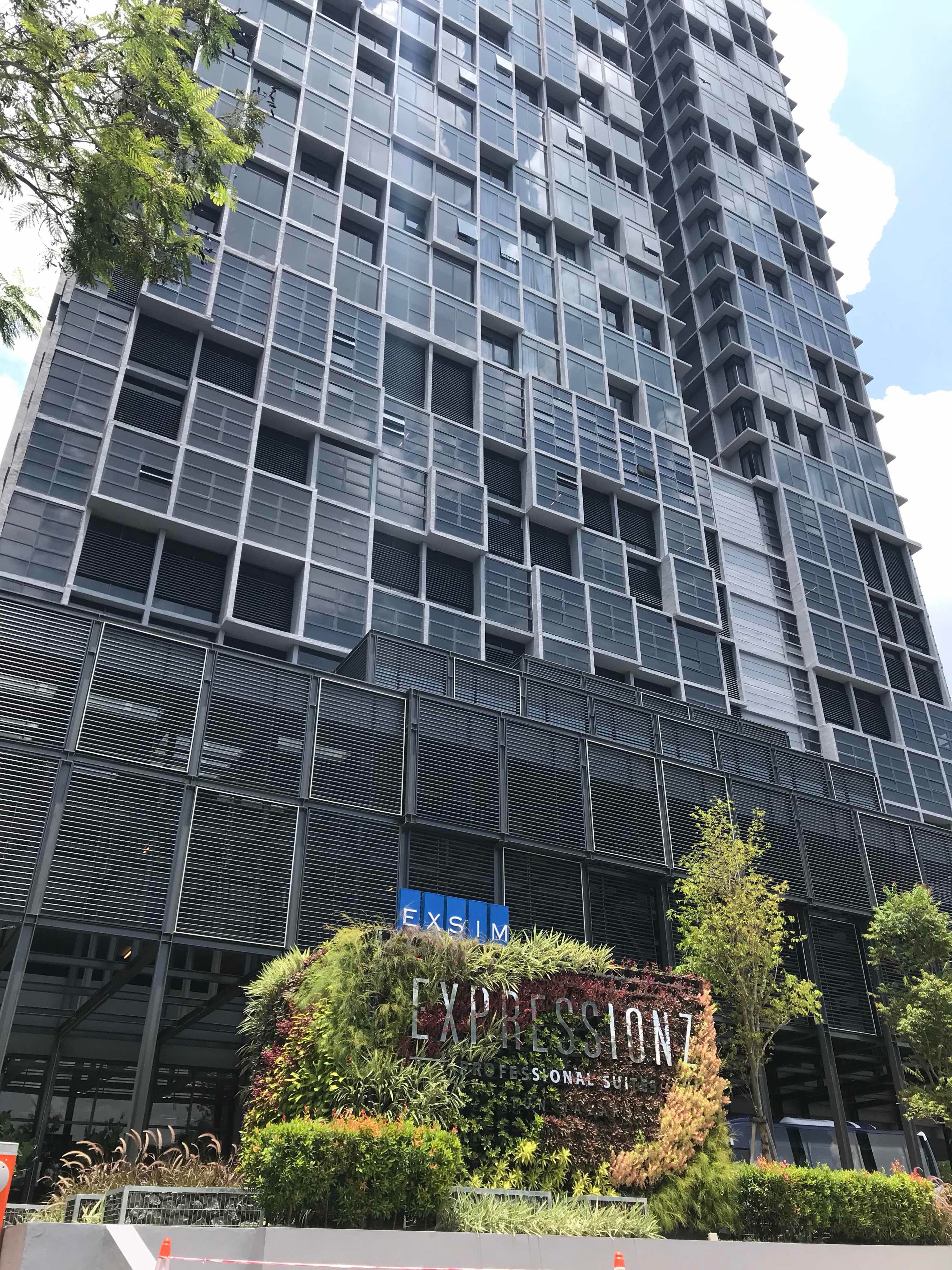 A modern high-rise building with a facade of large windows and a sign reading "EXPRESSION7 PROFESSIONAL SUITES".