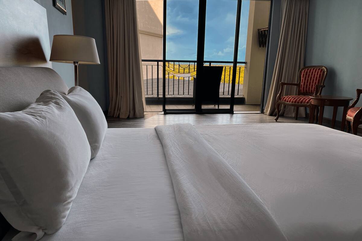 Une chambre d’hôtel avec un grand lit, une chaise, une table et une vue sur l’extérieur.