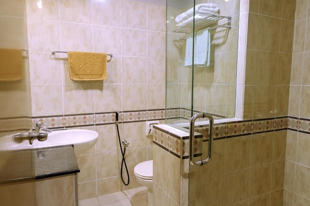 A bathroom with a glass-enclosed shower, a sink, and a toilet.