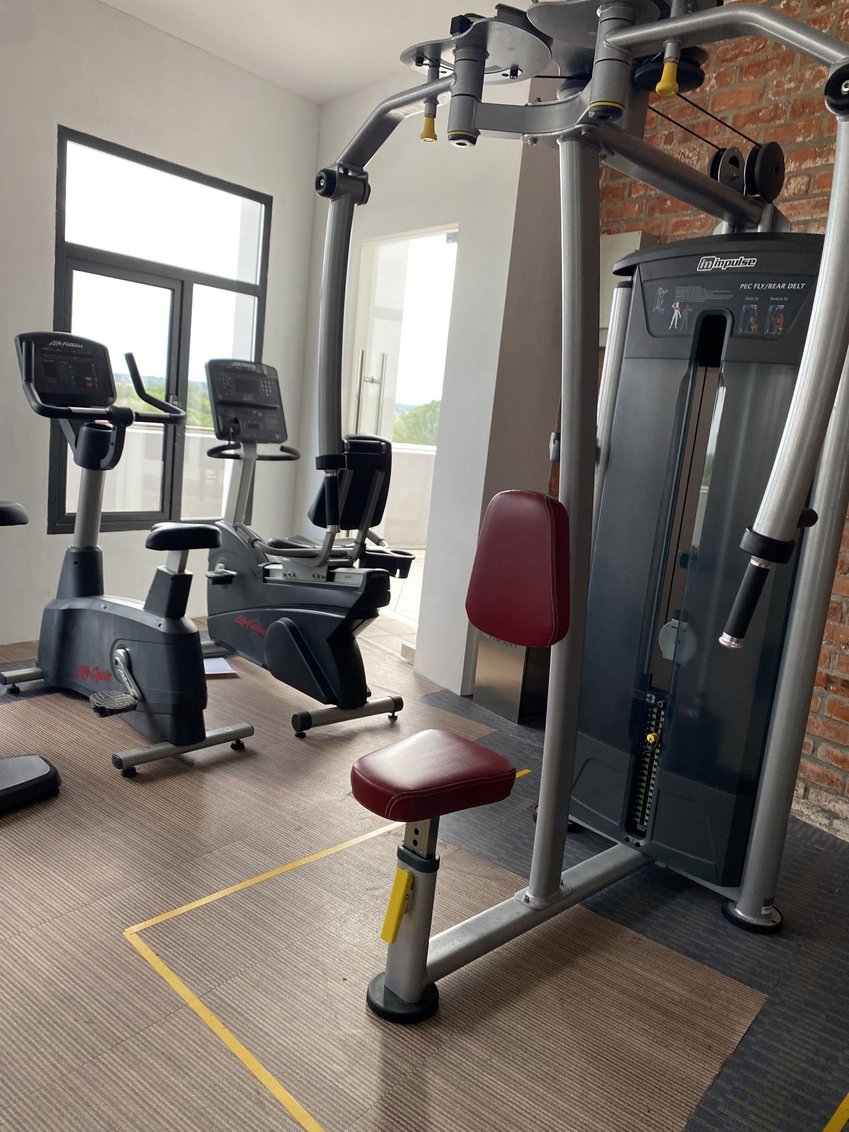 Une salle de sport équipée de divers appareils, notamment des tapis de course, un vélo d’appartement et une machine de musculation.