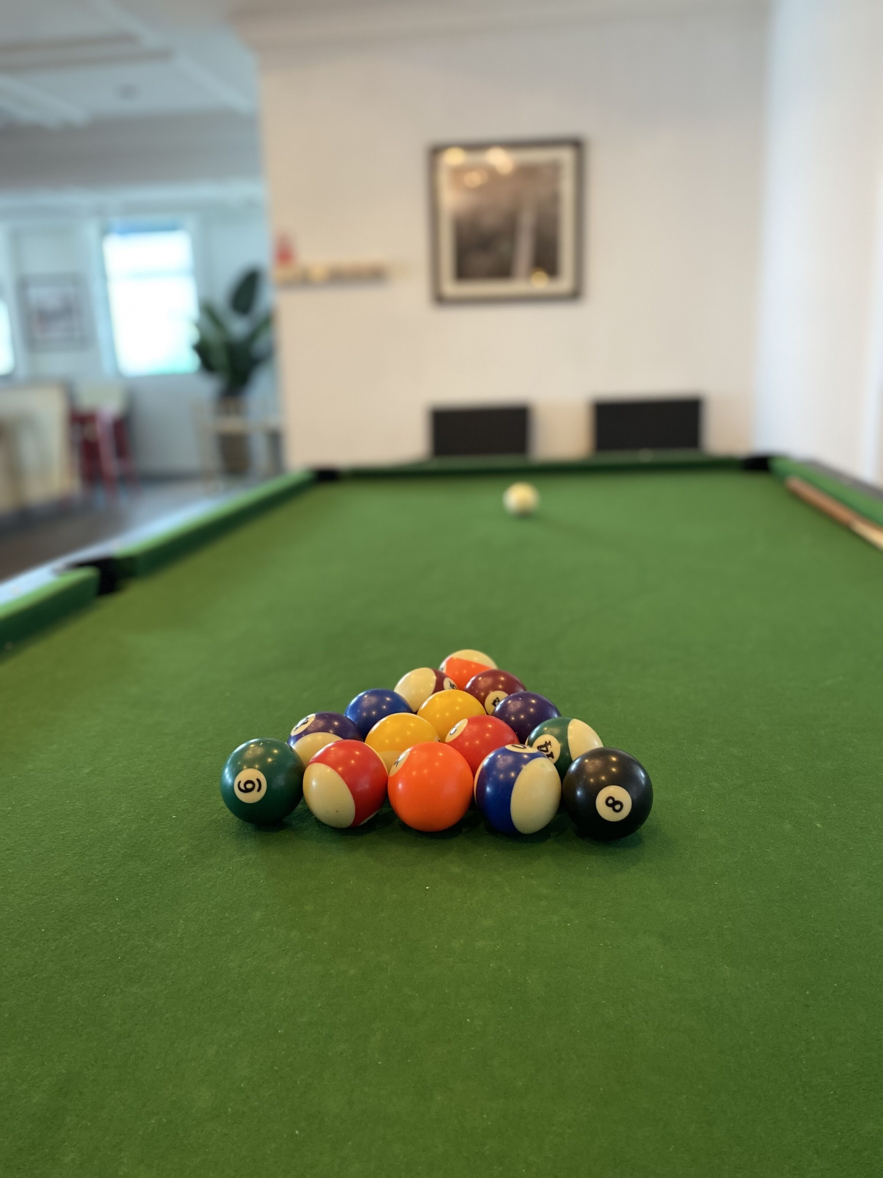 A pool table with a pyramid of billiard balls in the center.