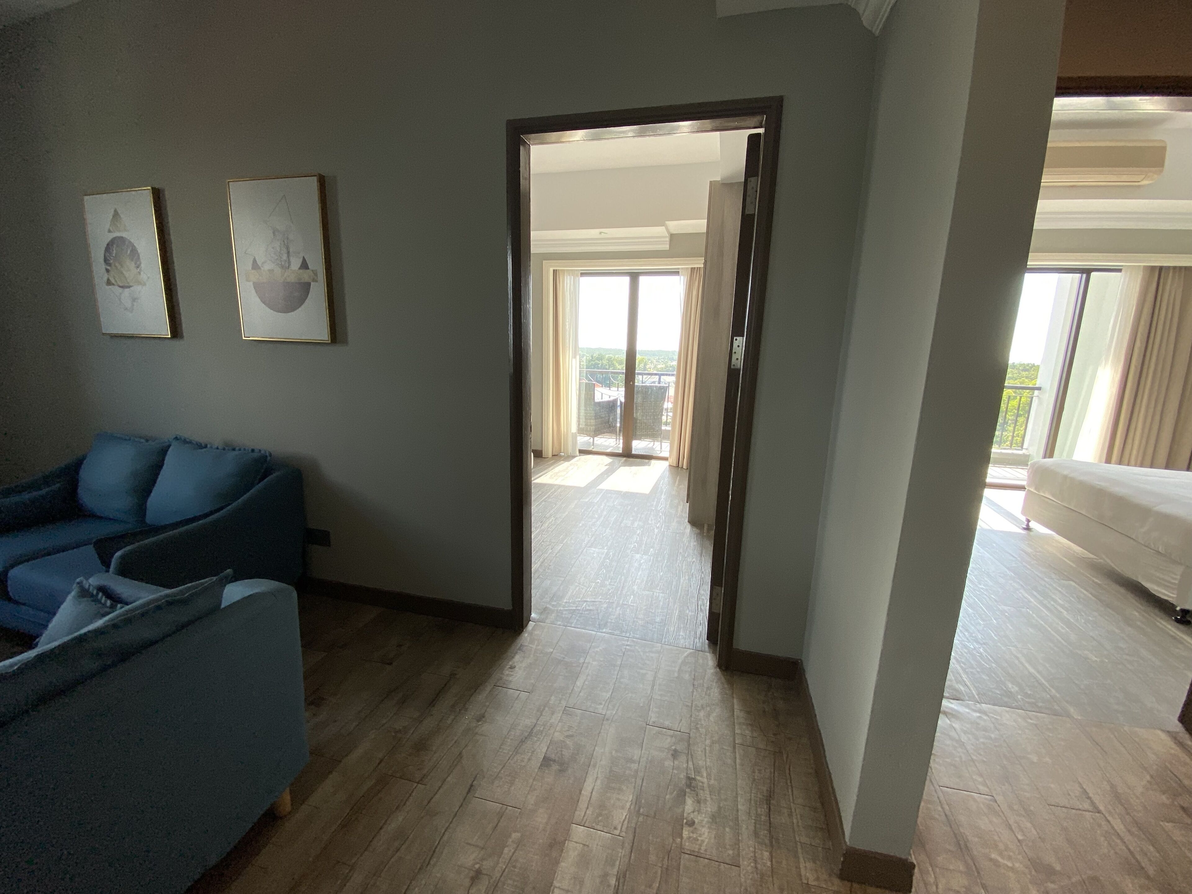 A modern living room with a blue sofa, wooden flooring, and a view to a balcony.