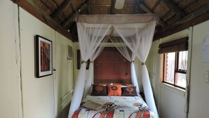 A bed with a canopy, a framed picture on the wall, and a window with a curtain. - Kruger Inn Backpackers (Nkomazi)