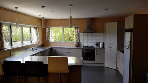 Una cucina moderna con un'isola grande, sgabelli da bar, un piano cottura a gas e un frigorifero.