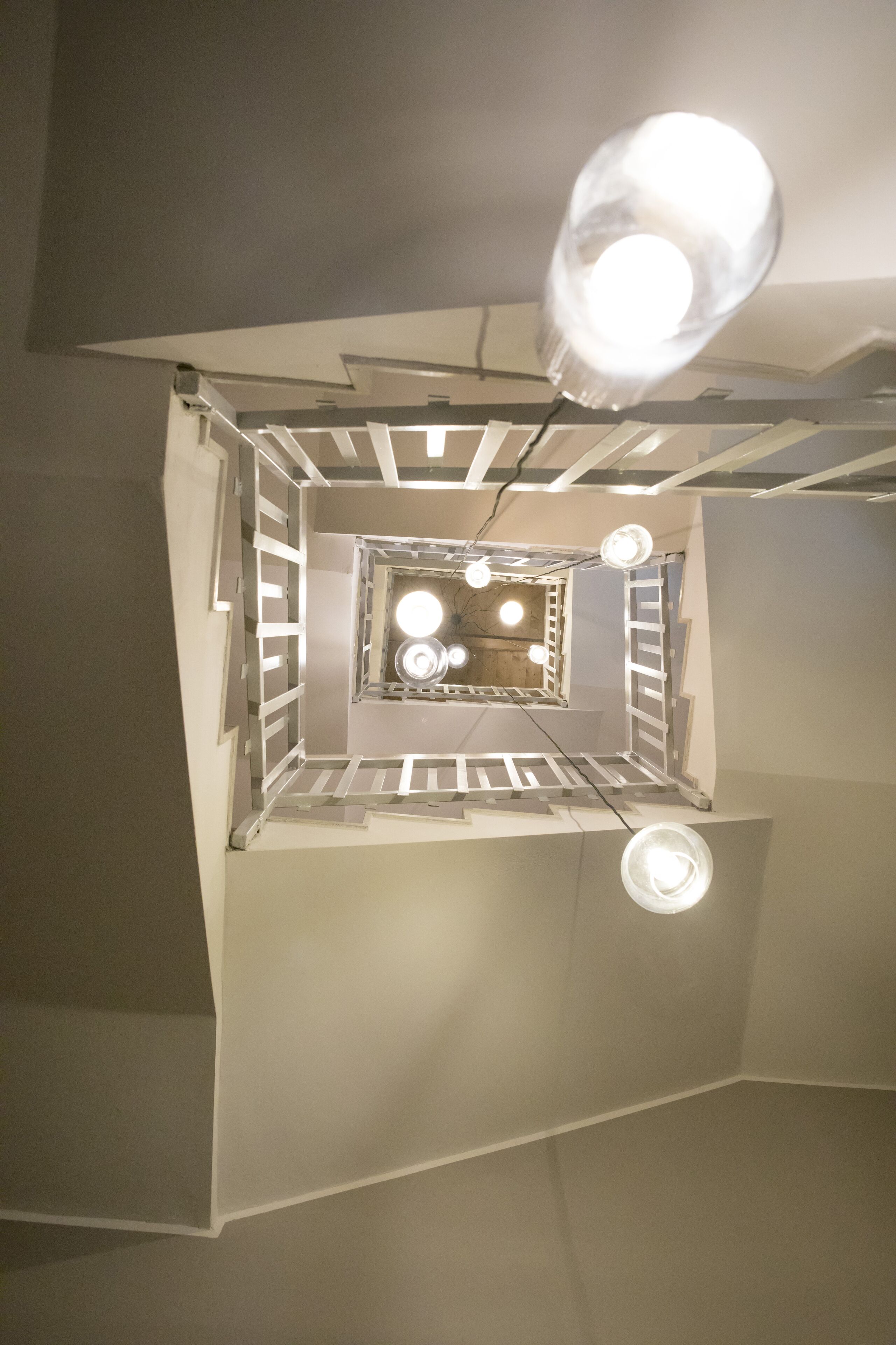 Un interior moderno con una escalera central, iluminación empotrada y un muro espejado.