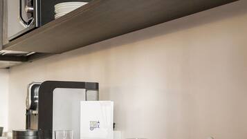 A modern kitchen with a coffee machine, a wine glass, and neatly arranged plates and cutlery.