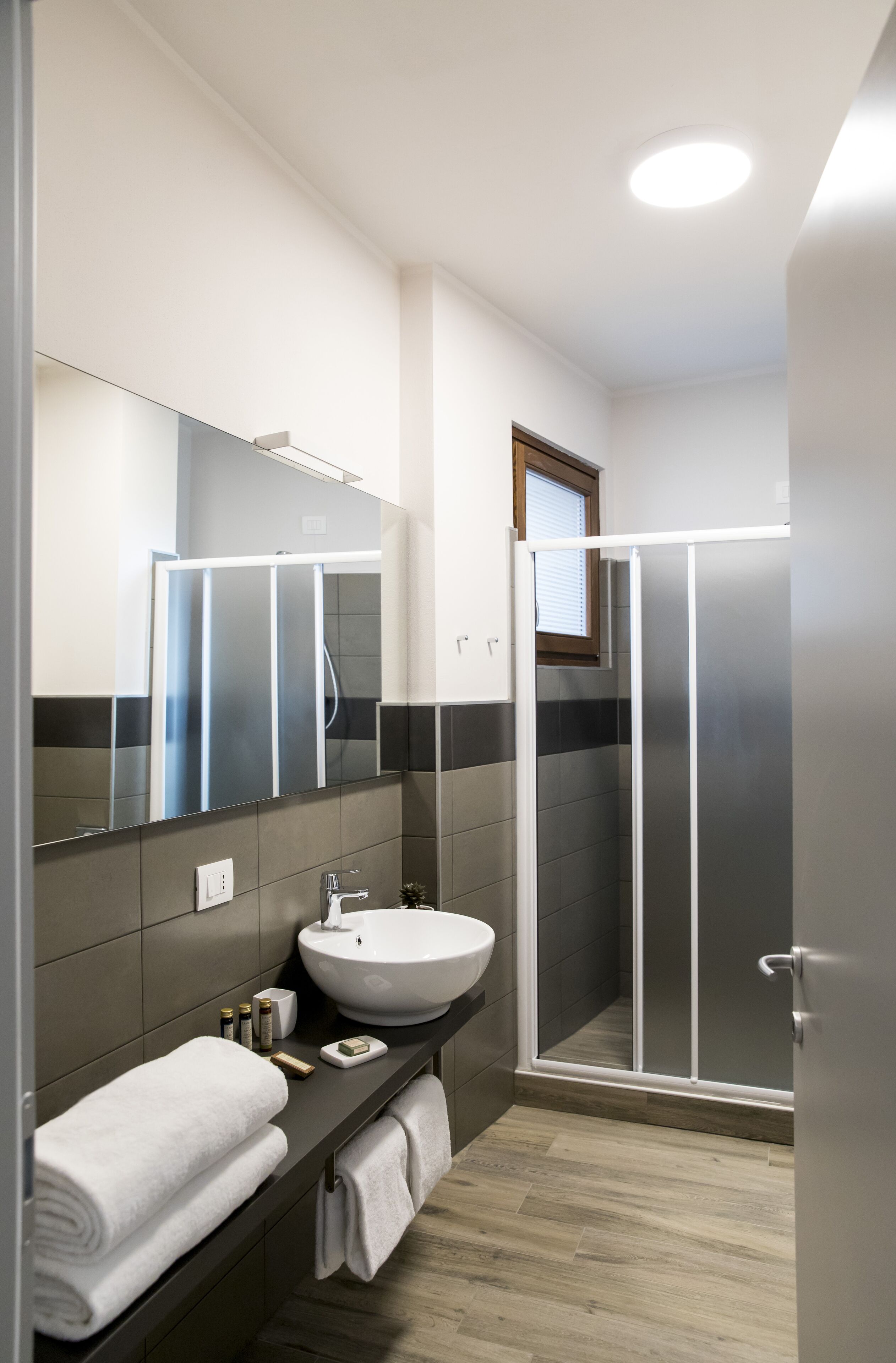A modern bathroom with a large mirror, a white sink, and a glass shower enclosure.