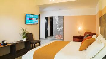 Une chambre d’hôtel moderne dotée d’un grand lit, d’un bureau avec un ordinateur portable, d’une télévision et d’une porte donnant accès à une salle de bain.
