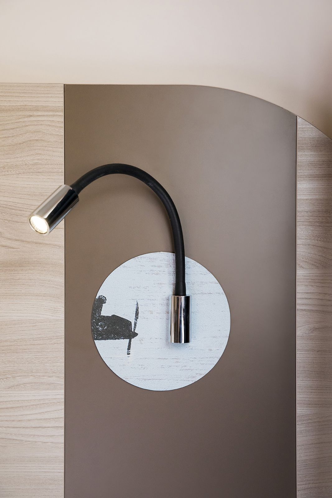 A wall-mounted light fixture with a curved design and a circular element.