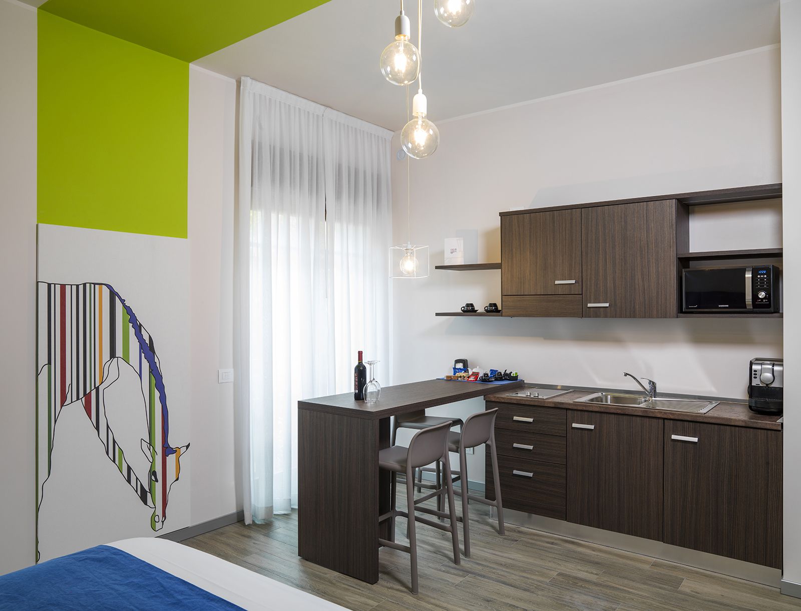 A modern kitchen with dark wood cabinets, a built-in microwave, and a bar area with stools.