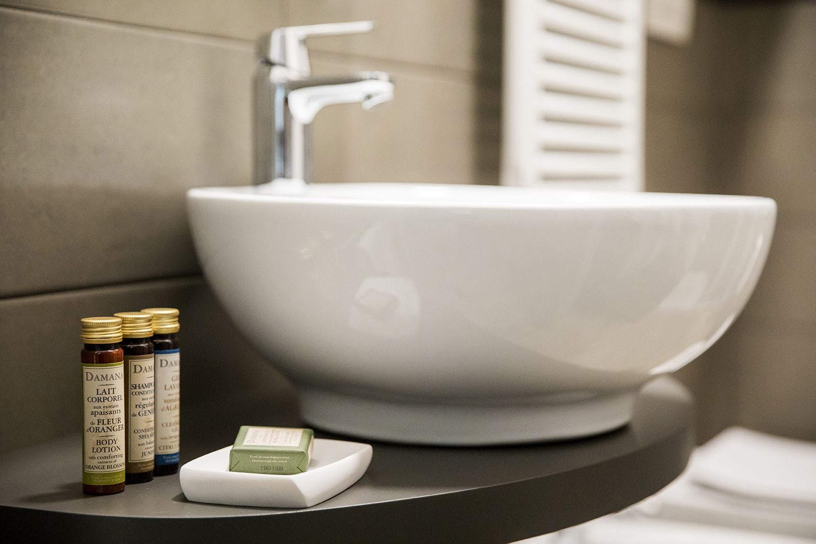 A bathroom sink with toiletries including body lotion and shampoo.