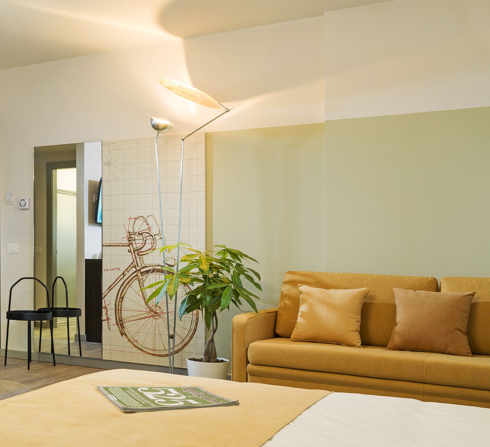 A modern living room with a sofa, a coffee table, a potted plant, and a bicycle sculpture.