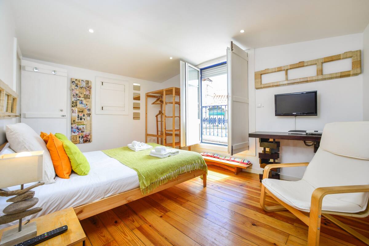 Ein Schlafzimmer mit einem Bett, einem Sessel, einem Fernseher und einem Fenster.
