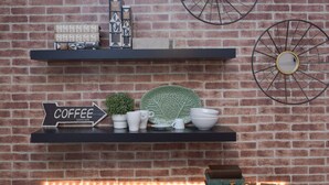 A brick wall with a shelf displaying coffee-related items and a sign that says "COFFEE SERVED HERE". - LxWay Apartments Graça - Santa Marinha (Lisbon)