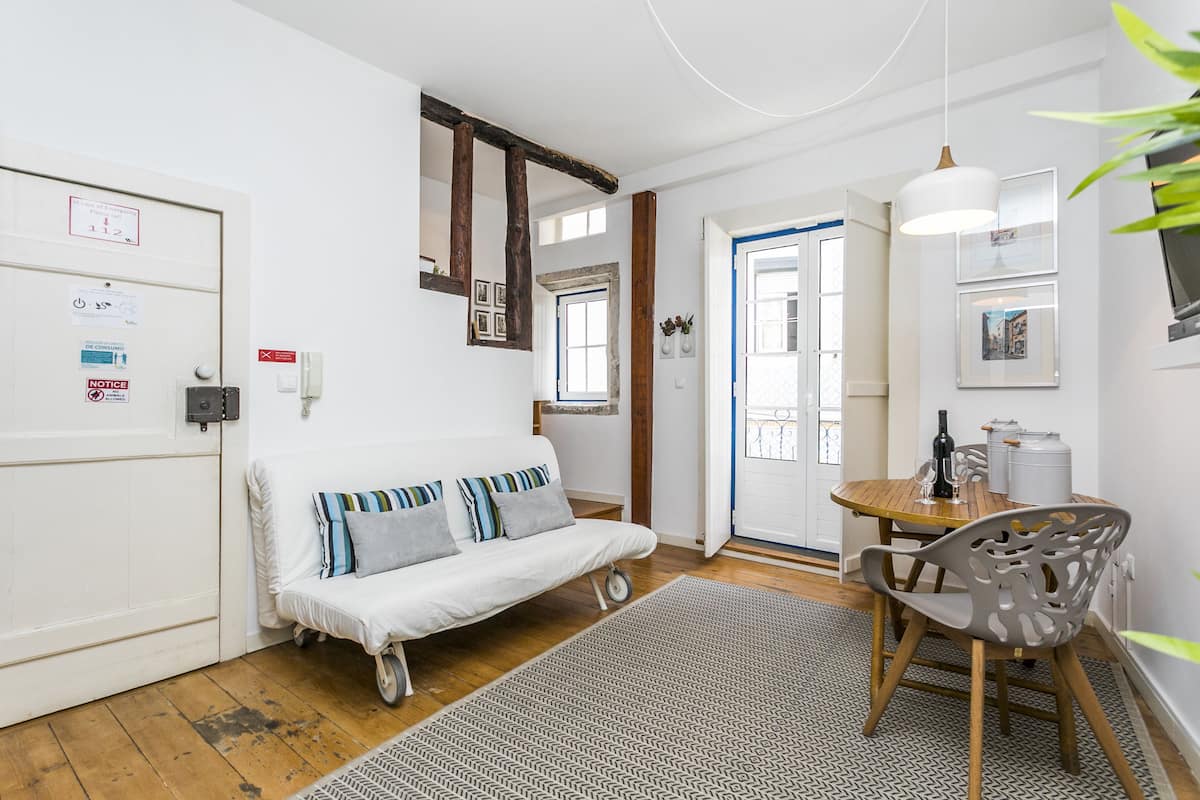 Ein gemütliches Wohnzimmer mit einem weißen Sofa, einem Holzesstisch und einem gemusterten Teppich.