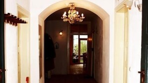 A hallway with wooden flooring, an arched doorway, and a chandelier. - Maurushaus (Fuessen)