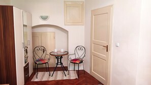 Un pasillo estrecho con dos sillas, una mesita y una puerta.
