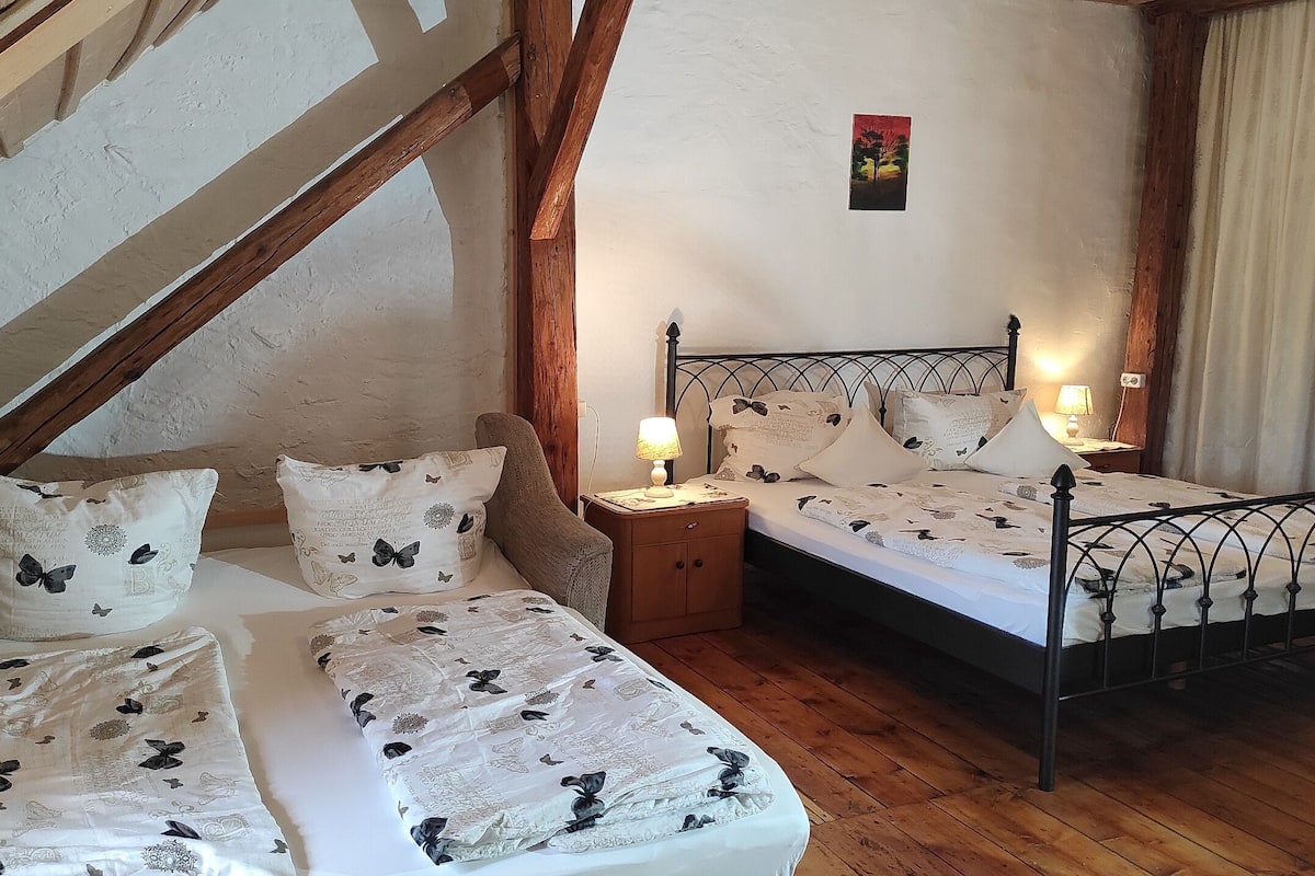 Un dormitorio con cama estilo loft, una mesita de noche con lámpara y un pequeño cuadro en la pared.