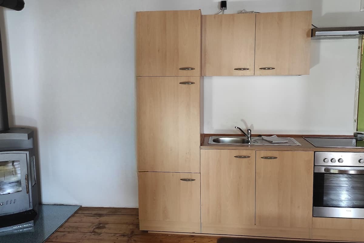 Una cocina compacta con armarios de madera, horno integrado y estufa.
