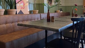 A restaurant with a booth seating area, a marble table, and hanging wicker lamps.