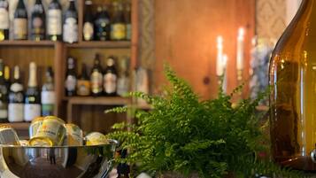 Zona de bar con una variedad de botellas, un bol con aperitivos y una planta en maceta.