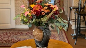 A wooden table with a vase of flowers in the center.