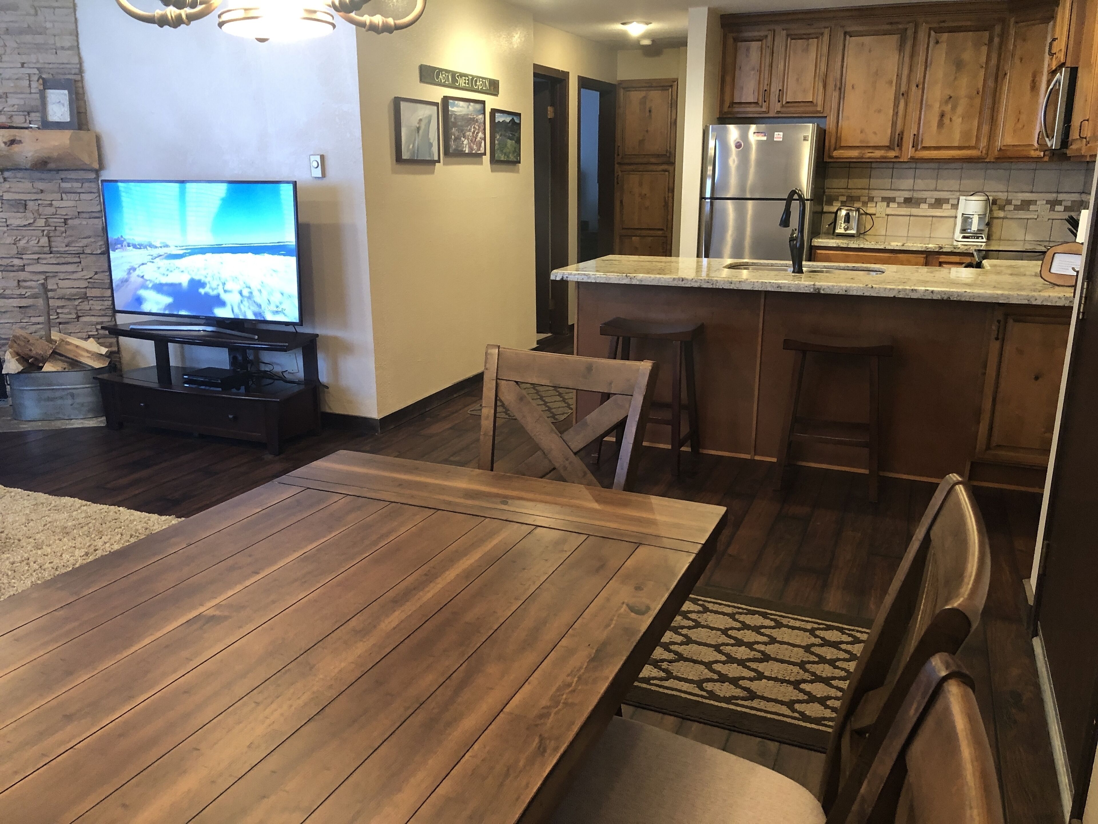 A modern kitchen with wooden cabinets, a stainless steel refrigerator, and a built-in island with bar stools.