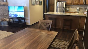 A modern kitchen with wooden cabinets, a stainless steel refrigerator, and a built-in island with bar stools.