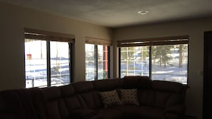 A living room with a sectional sofa and a round coffee table. There are large windows providing a view of a snowy landscape. - Giant Step 3 Condo!  Ski-in/Ski-Out. Completely Remodeled!  WI-FI (Brian Head)