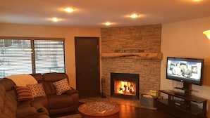 A cozy living room with a fireplace, a sofa, a television, and a coffee table. - Giant Step 3 Condo!  Ski-in/Ski-Out. Completely Remodeled!  WI-FI (Brian Head)