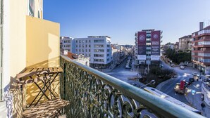 A balcony with a metal railing overlooking a city street with buildings and parked cars. - LxWay Apartments Largo de Santa Bárbara (Lisbon)