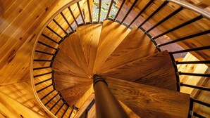 A wooden spiral staircase with a metal handrail and wooden steps.