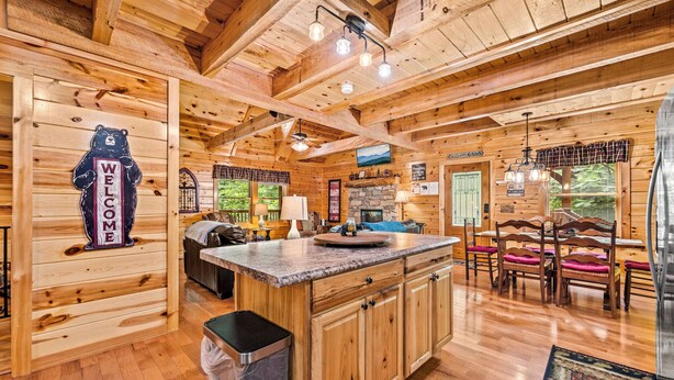 A wooden cabin interior with a central island, wooden walls, and a bear welcome sign.