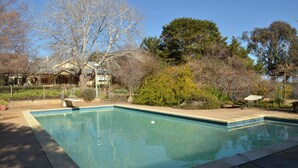 Une piscine rectangulaire dont les bords sont recouverts de carreaux, entourée d’une terrasse en béton.