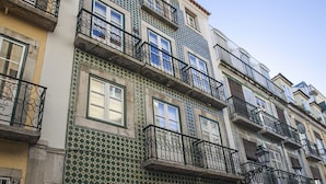 Eine Reihe mehrstöckiger Gebäude mit Balkonen, eine Kopfsteinpflasterstraße und ein strahlend blauer Himmel.