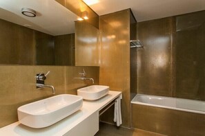 A modern bathroom with two sinks, a bathtub, and a large mirror.