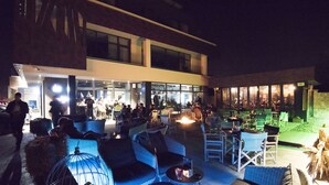 An outdoor seating area with wicker furniture and a glass enclosure. - Hotel Castellum (Cakovec)