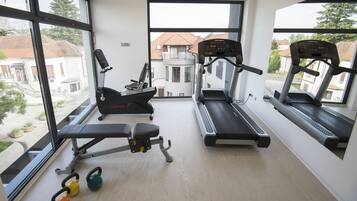 Un gimnasio con cintas de correr, una banca y pesas de mancuerna.