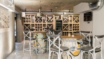 A bar area with a wine rack, round tables, and metal chairs.