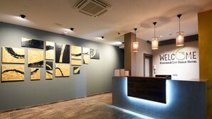 A reception area with a modern design, featuring a reception desk, wall art, and a 'Welcome' sign. - Hotel Castellum (Cakovec)