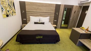 Une chambre d’hôtel équipée d’un lit, d’une table de chevet, d’un petit bureau et d’un climatiseur fixé au mur.