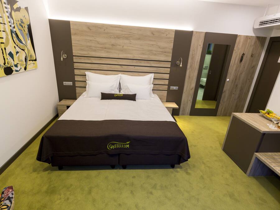 Habitació d'hotel amb llit, una taula de nit, un escriptori petit i aire condicionat fixat a la paret.