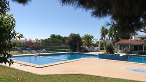 A swimming pool with lounge chairs and umbrellas, surrounded by grass and trees. - Algarve luxury seaview apartment with pool near beaches  (Porches)
